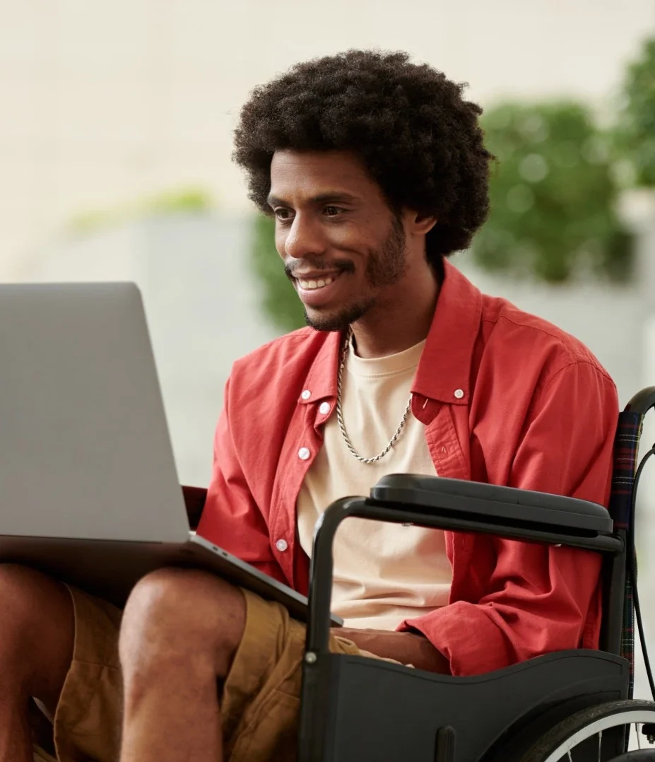 Disabled man in wheelchair looking at laptop and smiling