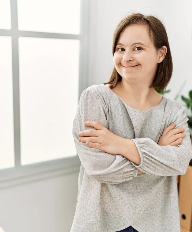 Woman with down syndrome smiling and looking at the camera with her arms crossed
